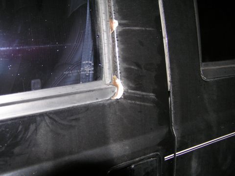 2000 Ford Excursion - Close-up of the side door frame of a black 2000 Ford Excursion, showing sealant and window trim details.