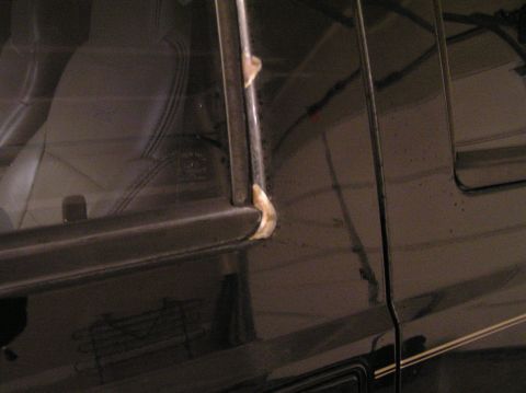 2000 Ford Excursion - Close-up of a black SUV's door frame, showing sealant around the window trim.