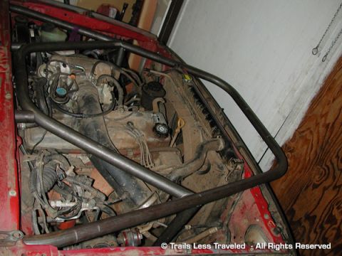 1977 Ford F-150 - The engine bay of a vehicle is visible, a roll cage structure and various engine components.