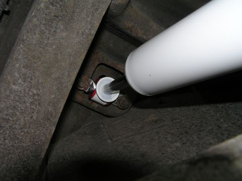 2000 Ford Excursion - Close-up of a white shock absorber with a red and white bushing attached to the vehicle's frame.