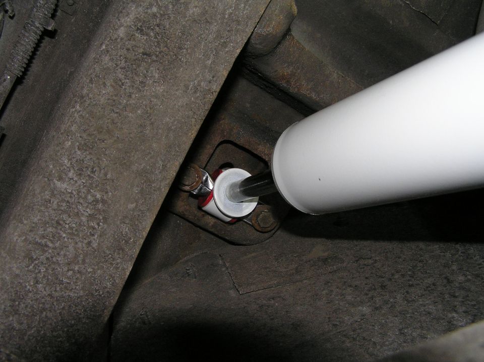 White shock absorber mounted to a rusty vehicle frame bracket