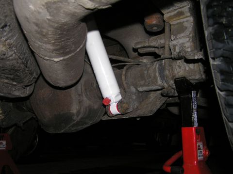 2000 Ford Excursion - Undercarriage view of a vehicle's rear suspension, showing a white shock absorber and exhaust system.