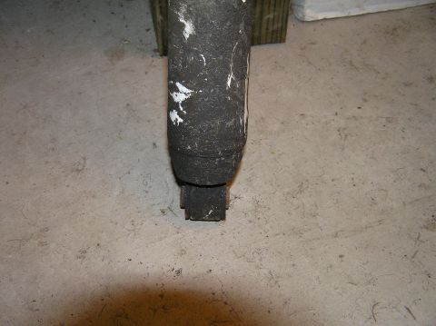 2000 Ford Excursion - A dirty shock absorber is shown in a close-up view against a concrete floor.