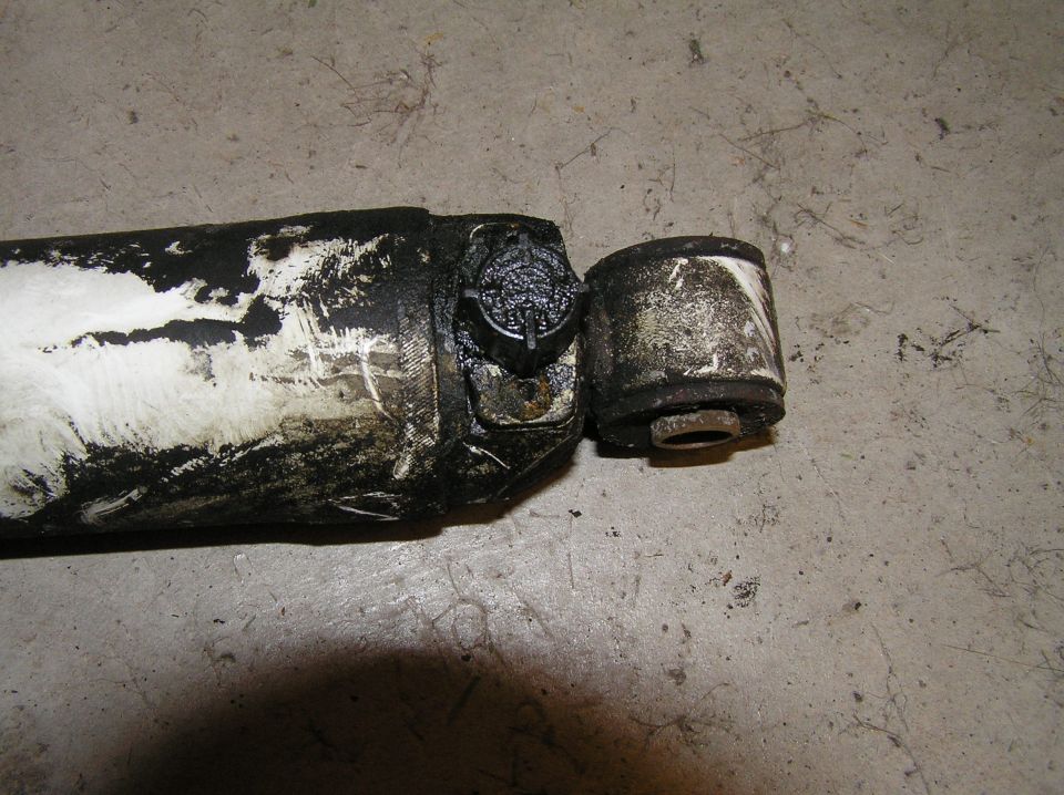 Worn shock absorber lower end with rubber bushing on concrete floor