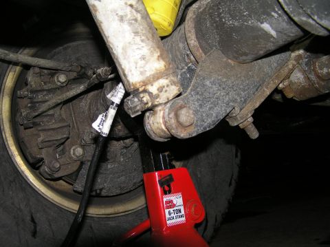 2000 Ford Excursion - Close-up view of the rear suspension and axle assembly of a vehicle, supported by a jack stand.
