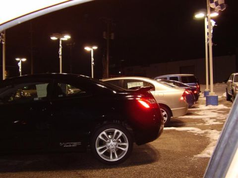 1997 Ford Taurus - Multiple vehicles are parked in a lot at night, illuminated by overhead lights.