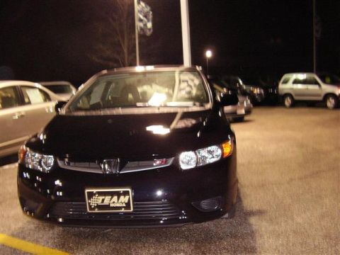 1997 Ford Taurus - A black Honda Civic is parked at a dealership lot at night, with other vehicles visible in the background.
