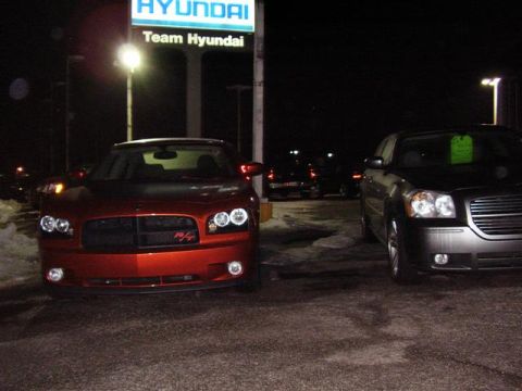 1997 Ford Taurus - A red Dodge Charger R/T is parked in front of a Hyundai dealership at night, with another car to its right.