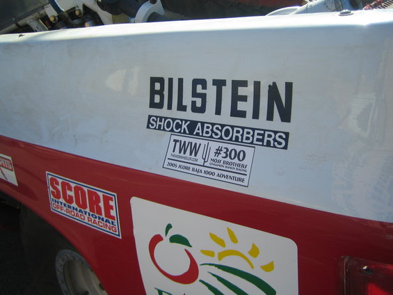 Close-up of BILSTEIN SHOCK ABSORBERS decal and SCORE logo on a red and white race truck panel