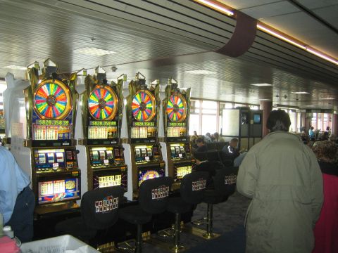 1968 Ford Mustang - Several slot machines are lined up in a casino or gaming area, with people seated in the background.