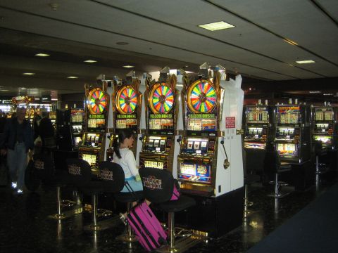 1968 Ford Mustang - A row of slot machines with colorful spinning wheels and digital displays are seen in a casino or airport terminal.