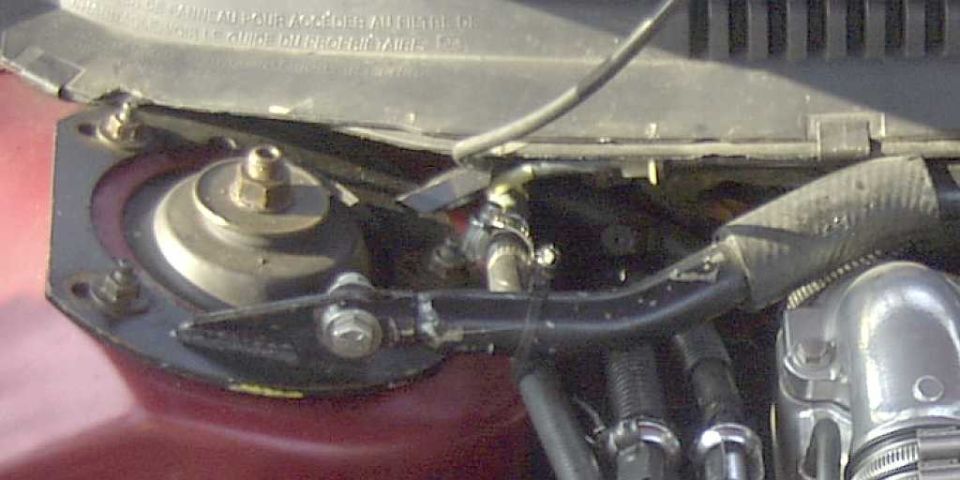 Close-up of engine bay components, including a strut mount and hoses