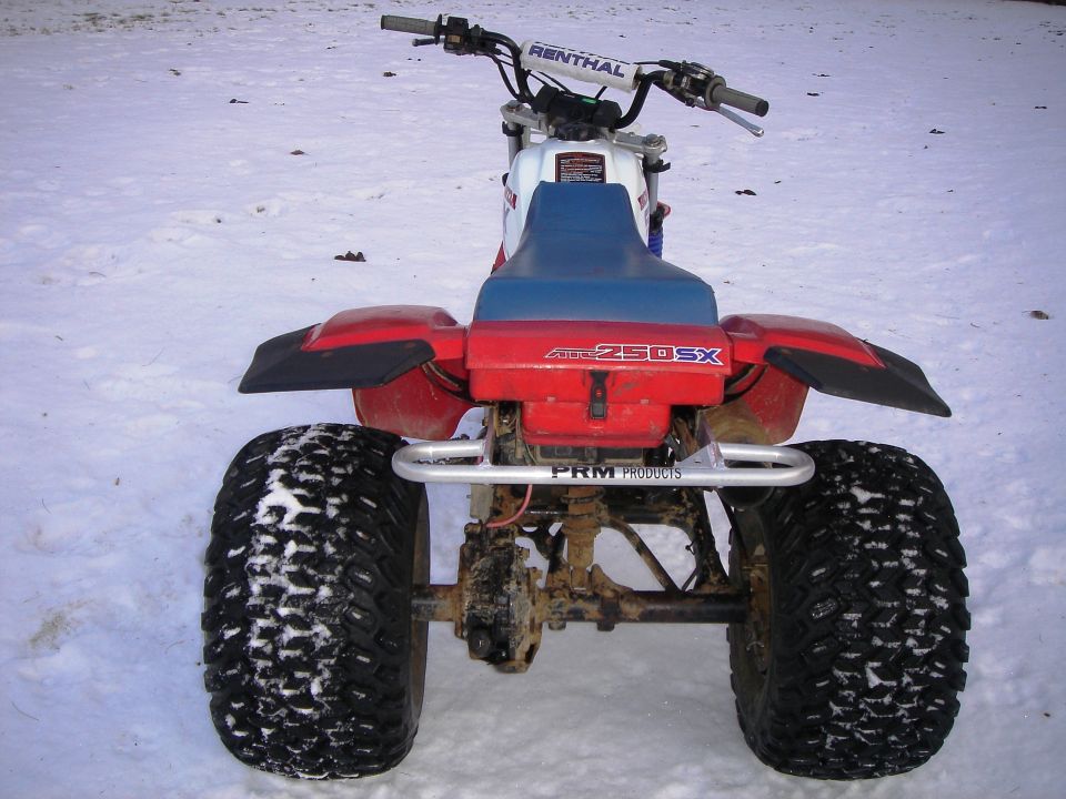 Red Honda 250SX three-wheeler ATV rear view on snow with PRM grab bar