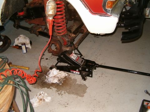 1979 Ford Bronco - Vehicle suspension components are visible with a jack supporting the frame and tools scattered around.