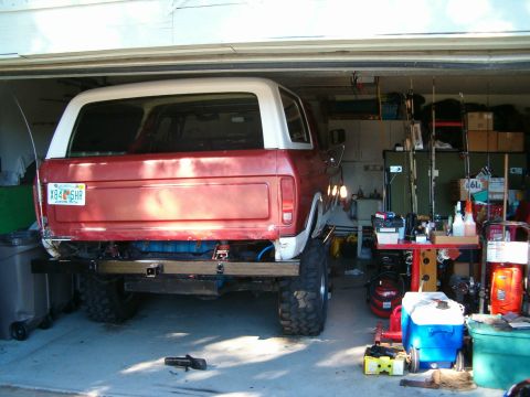 1979 Ford Bronco - 1979 Ford Bronco seen from the rear, parked inside a garage with fishing gear and other items visible.