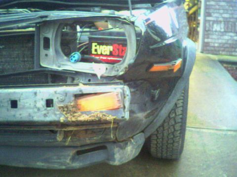 1987 Volkswagen Golf - The front of a car is damaged, with the headlight assembly removed and the bumper showing signs of impact and debris.