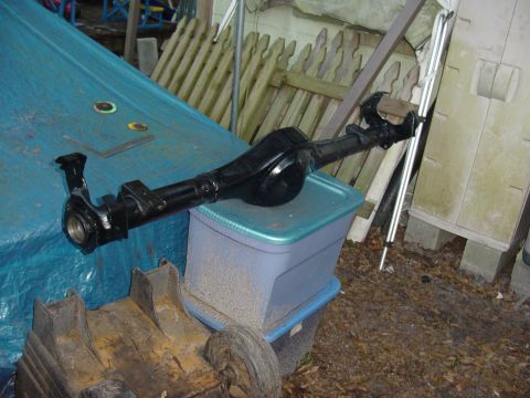 1989 Ford Bronco - A black rear axle assembly is visible, resting on a blue tarp and a plastic storage bin.