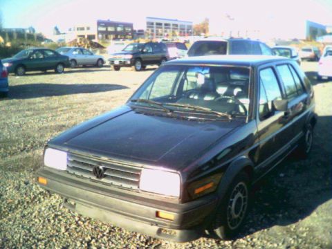 1987 Volkswagen Golf - A dark 1987 Volkswagen Golf is parked in a lot with other vehicles.