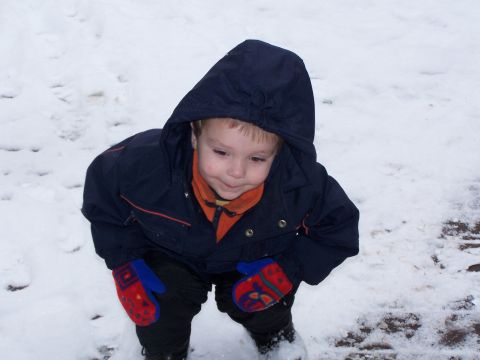 1986 Ford Bronco - A young child is playing in the snow, dressed warmly in a jacket and mittens.