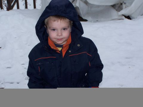 1986 Ford Bronco - A young child wearing a hooded jacket is sitting in the snow, looking towards the camera.
