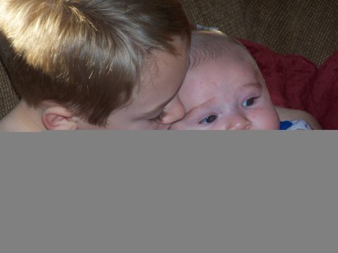 1986 Ford Bronco - An older child leans in close to a baby, sharing a tender moment.