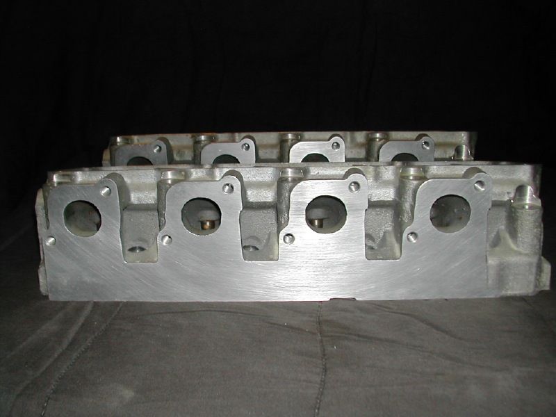 Bare aluminum cylinder head showing four machined ports and bolt holes