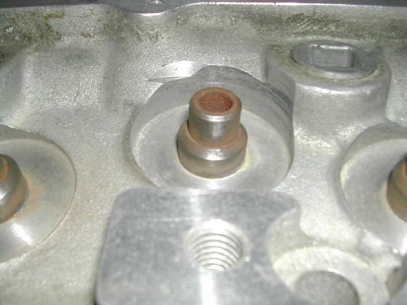 Close-up of a cylinder head valve guide boss with bronze guide and threaded stud hole