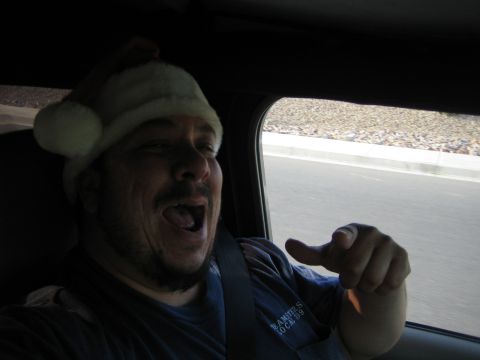 1968 Ford Mustang - Man in Santa hat points forward from inside a vehicle.