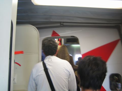 1968 Ford Mustang - Passengers board an airplane through an open door, with red accents visible on the fuselage.