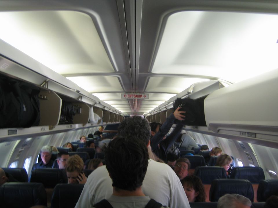 Airplane cabin interior with overhead bins open and passengers seated