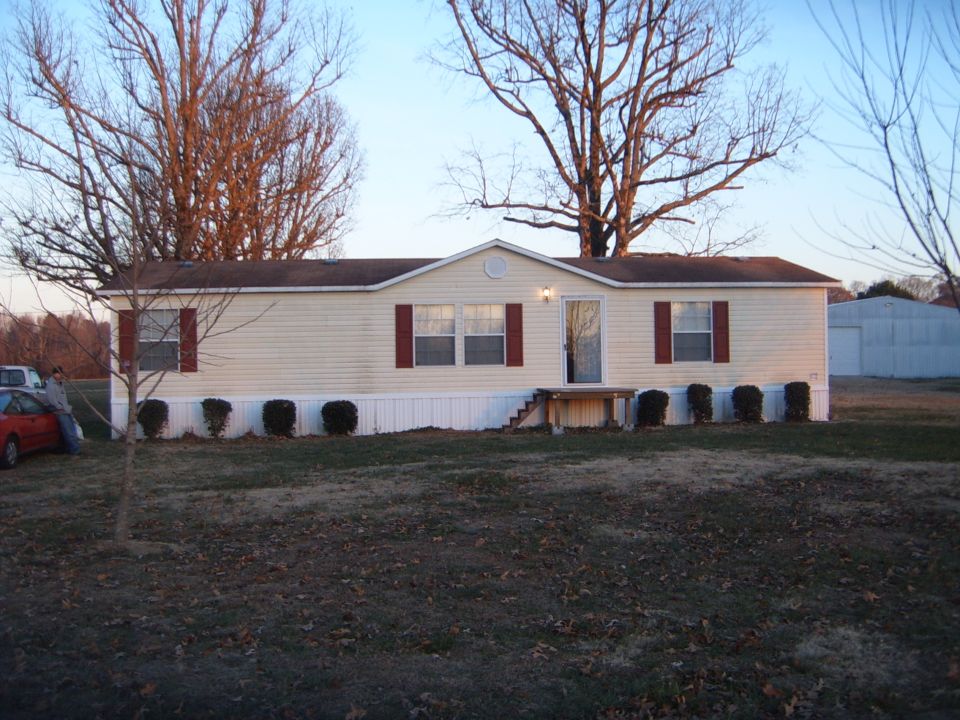 Mobile home with red car and white SUV parked nearby