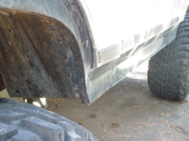 Close-up of a dirty wheel well and fender flare with a tire visible