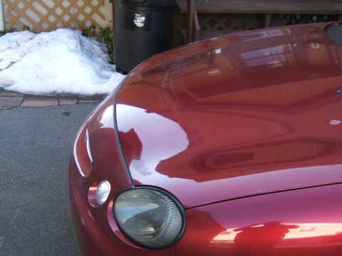 1998 Ford Taurus - The front corner of a red 1998 Ford Taurus is visible, with snow and a trash can in the background.