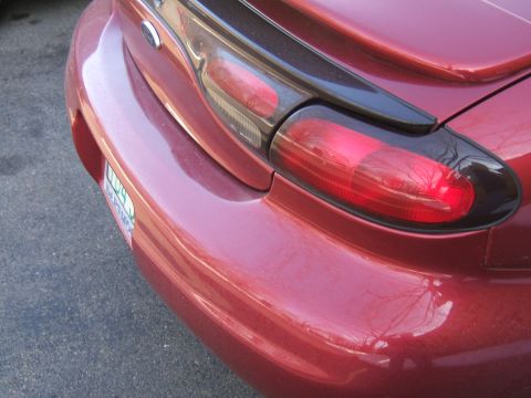 1998 Ford Taurus - Close-up of the rear bumper and taillight assembly on a red 1998 Ford Taurus.
