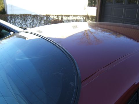 1998 Ford Taurus - The reflection on the car's roof shows trees and a garage door, indicating an outdoor setting.