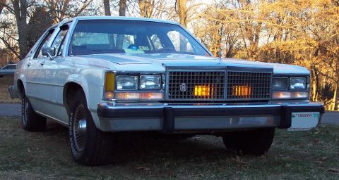 1985 Ford Crown Victoria LTD - Front view of a white sedan with a prominent grille and amber turn signals.