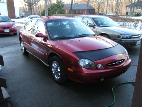 1998 Ford Taurus - Red 1998 Ford Taurus sedan parked in a driveway, partially covered by a car bra.