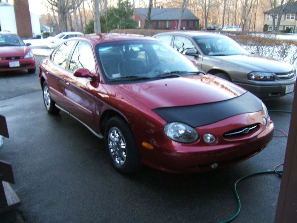 1998 Ford Taurus sedan with a black car bra, parked outside next to another car