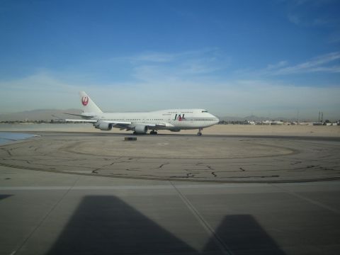 1968 Ford Mustang - A Japan Airlines Boeing 747 aircraft is seen on the tarmac under a clear blue sky.