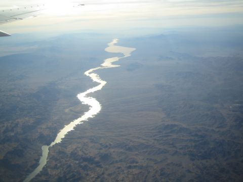 1968 Ford Mustang - An airplane wing is visible in the upper left corner of this aerial view of a winding river flowing through a vast, mountainous terrain.