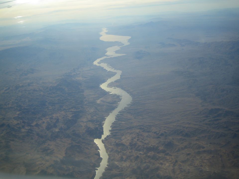 Aerial view of a wide, winding river cutting through a dry, mountainous desert