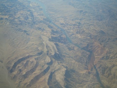 1968 Ford Mustang - An aerial perspective captures a river carving its path through a vast, arid mountain range.