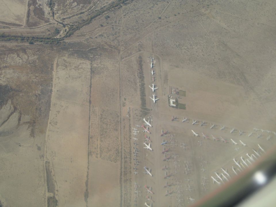 Aerial view of an airplane boneyard with rows of parked aircraft in a desert landscape