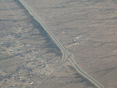 1968 Ford Mustang - An aerial perspective captures a canal system traversing a dry, arid region dotted with sparse housing.