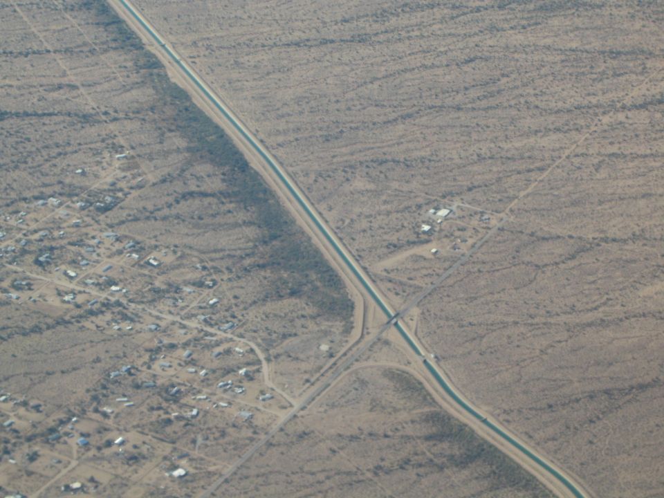 Aerial view of a canal running through a desert landscape with a small town on the left