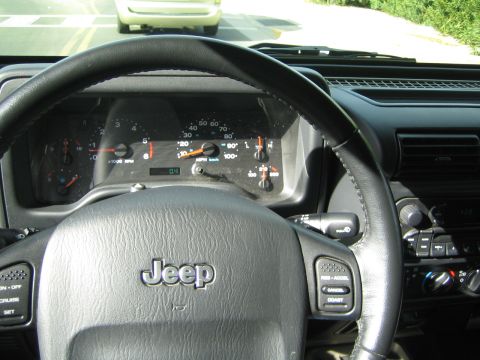 1968 Ford Mustang - The dashboard of a Jeep shows the speedometer and tachometer, with a white vehicle ahead on the road.