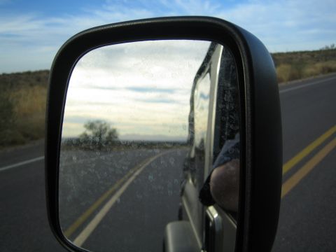 1968 Ford Mustang - View from the passenger side mirror while driving on a highway through a dry landscape.