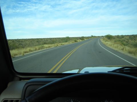 1968 Ford Mustang - View from inside a vehicle driving on a highway through a dry, arid landscape under a partly cloudy sky.