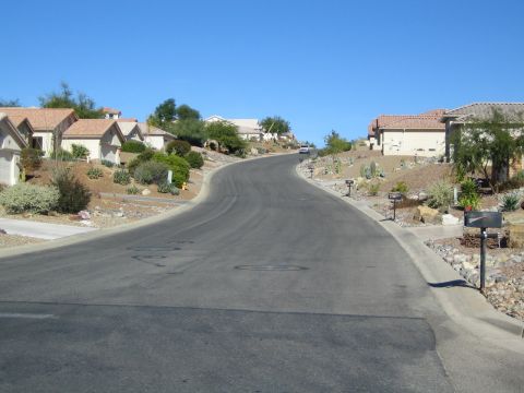 1968 Ford Mustang - A white SUV travels up a winding road in a desert-like suburban neighborhood under a clear blue sky.