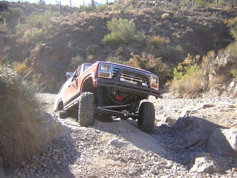 1984 Ford Bronco - This lifted 1980s Ford Bronco navigates a challenging rocky terrain on an off-road trail.